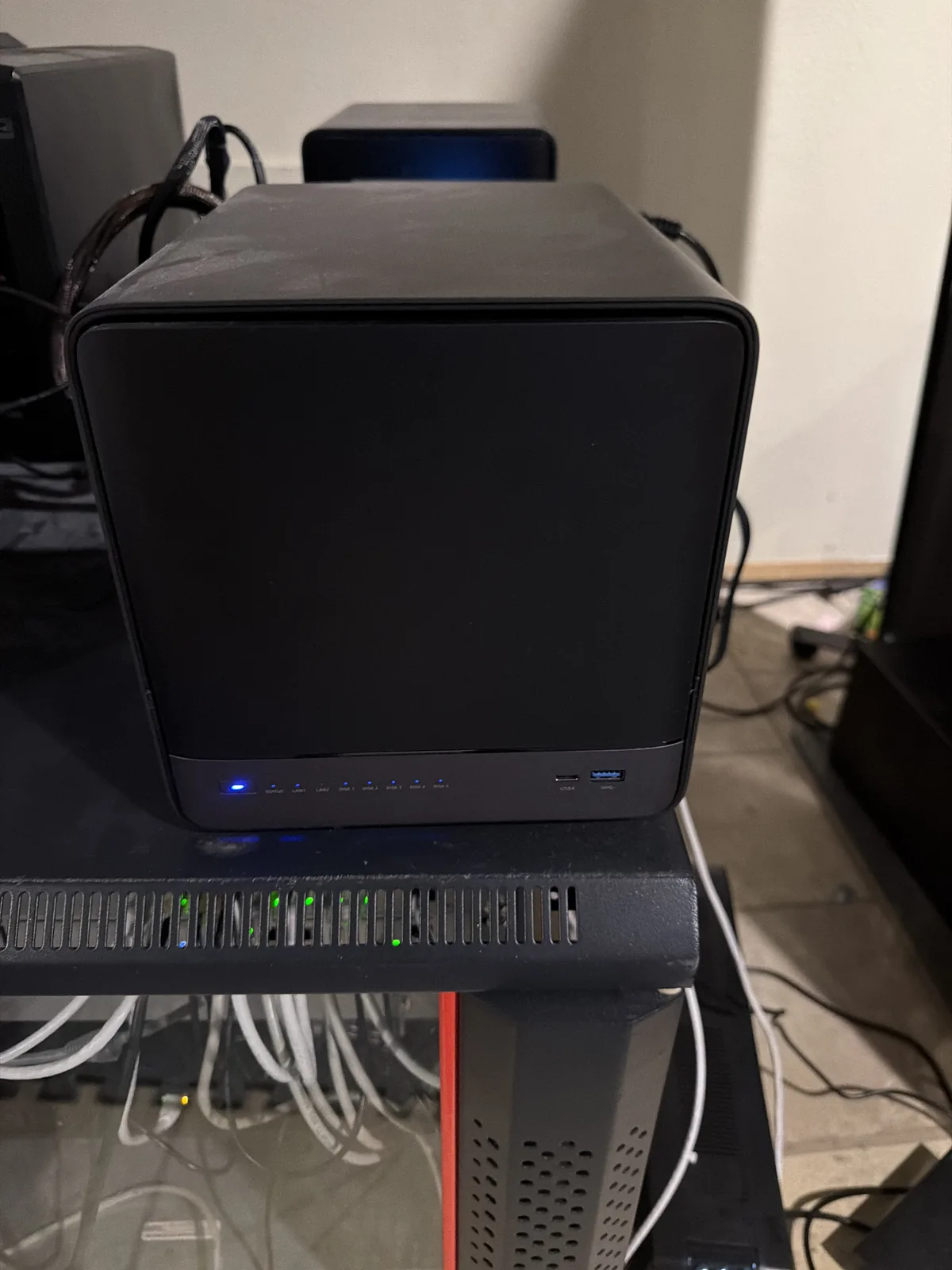 kratos, a Minisforum N5 Pro mini PC, sitting on a shelf beside networking gear with its status LEDs lit